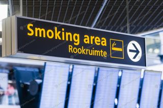 Black and yellow Smoking Area Rookruimte directional sign inside Schiphol Airport