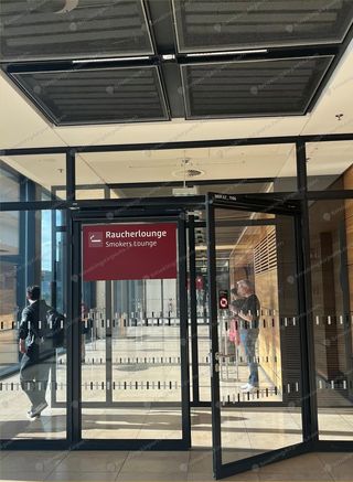 Glass-door entrance to BER Raucherlounge Smokers Lounge with passengers inside