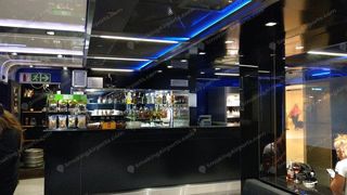 Dark interior bar area of CPT international departures smoking lounge with blue LED lighting and liquor bottles