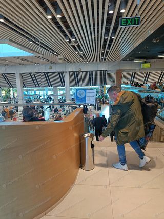 Upper level of Chisinau Airport terminal with smoking area directional sign and metal ashtray stand near staircase