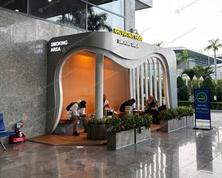 Curved outdoor smoking shelter with bench seating and ashtrays at Da Nang Airport