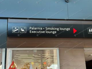 Dark overhead sign reading Palarnia Smoking Lounge and Executive Lounge with red arrow at Gdansk Airport