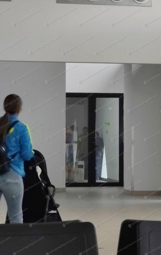 Glass-doored smoking booth inside IAS terminal airside waiting area with passengers visible