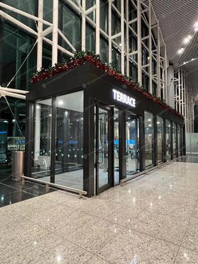 Enclosed black-framed glass Terrace smoking pavilion with holiday decorations at Istanbul Airport