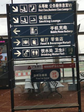 KMG level 3F wayfinding sign pointing down toward First Class Lounge V9 and smoking lounge