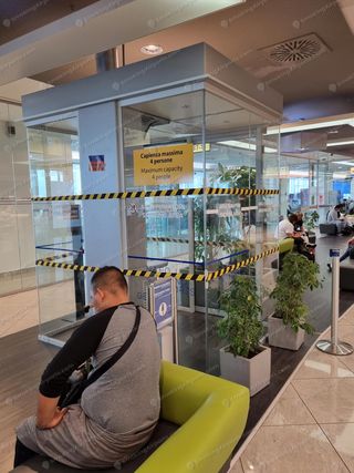Closed glass smoking cabin at NAP sealed with yellow hazard tape, maximum 4 persons sign visible