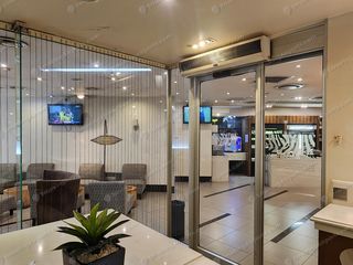 Glass-walled lounge interior with armchairs and TV screens at JNB Terminal A