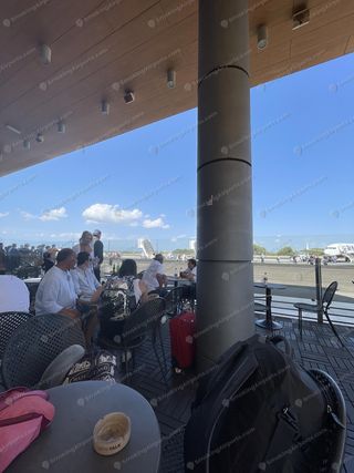 Covered outdoor airside terrace at Zadar Airport with passengers seated, runway and aircraft visible in background